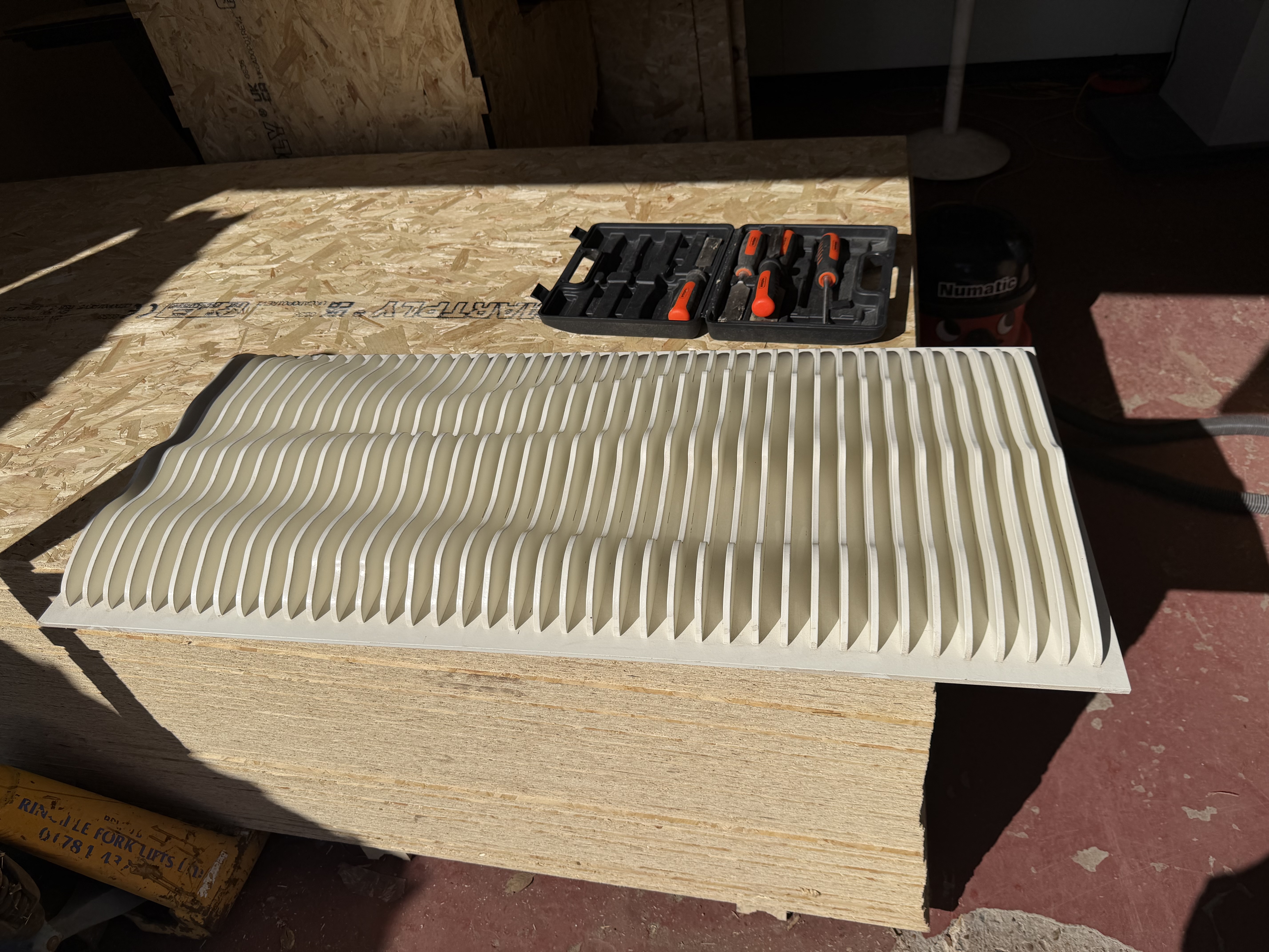 Repeated curved profiles assembled into a layered panel on a workbench